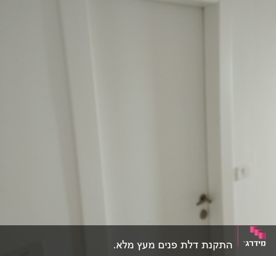 דלת לבנה עם ידית מתכת על קיר לבן